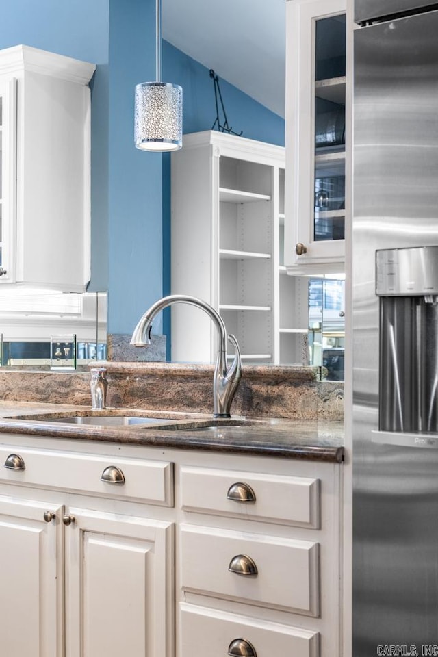 kitchen with lofted ceiling, white cabinetry, hanging light fixtures, and stainless steel fridge with ice dispenser