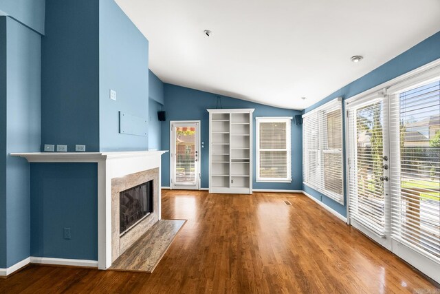 unfurnished living room featuring wood-type flooring, vaulted ceiling, and a premium fireplace