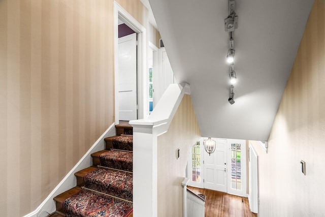 staircase with hardwood / wood-style floors and vaulted ceiling