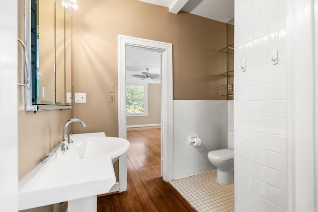 bathroom featuring hardwood / wood-style flooring, toilet, sink, tile walls, and ceiling fan