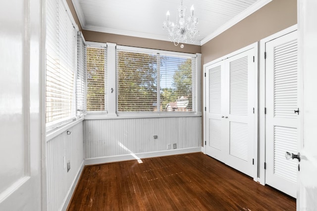 unfurnished bedroom with crown molding, a notable chandelier, multiple closets, and dark hardwood / wood-style flooring