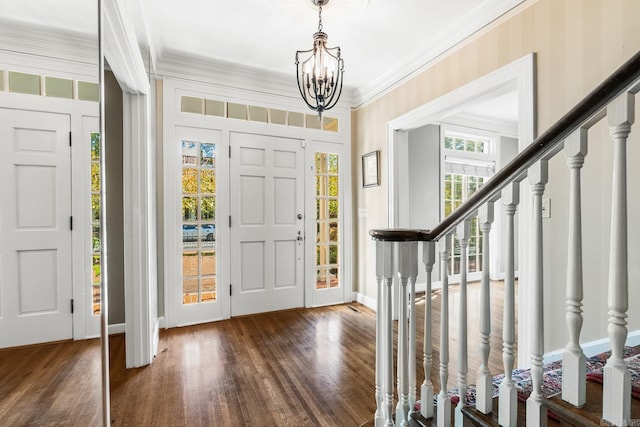 foyer entrance with dark wood-type flooring, a notable chandelier, and crown molding