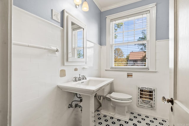 bathroom with heating unit, tile walls, toilet, crown molding, and tile patterned floors