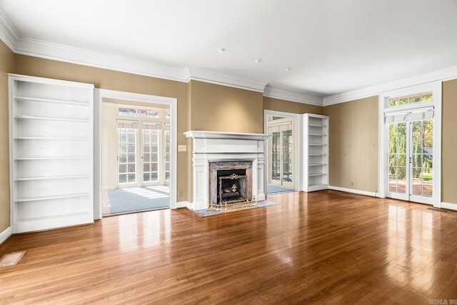 unfurnished living room featuring hardwood / wood-style floors, crown molding, and a fireplace