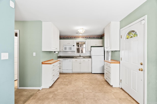 kitchen featuring sink, white cabinets, and white appliances