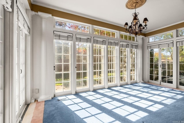 unfurnished sunroom featuring ornate columns and a notable chandelier