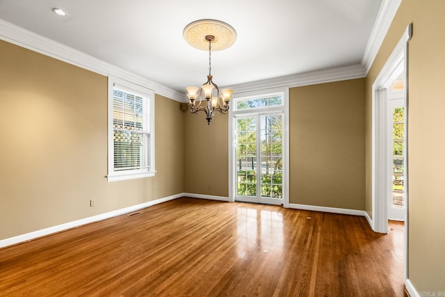 spare room with a healthy amount of sunlight, ornamental molding, a chandelier, and dark hardwood / wood-style floors