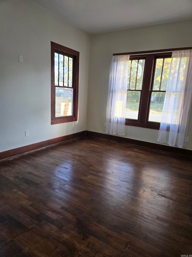 unfurnished room with dark hardwood / wood-style flooring and a healthy amount of sunlight