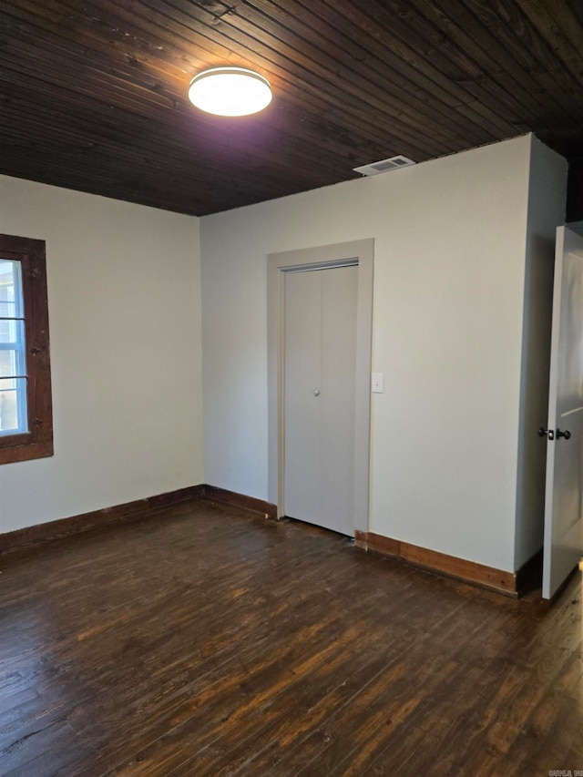 spare room featuring dark hardwood / wood-style floors and wooden ceiling