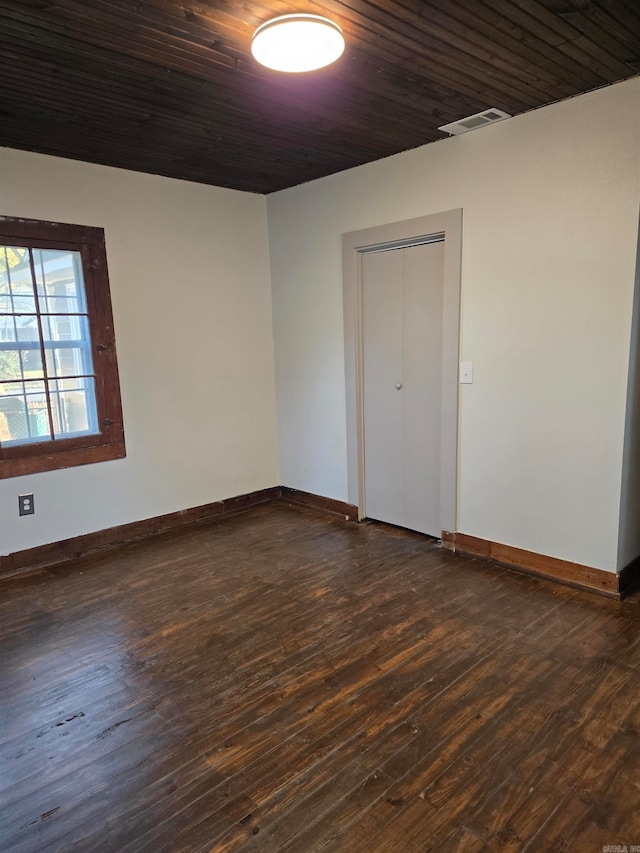 empty room with dark hardwood / wood-style flooring and wooden ceiling