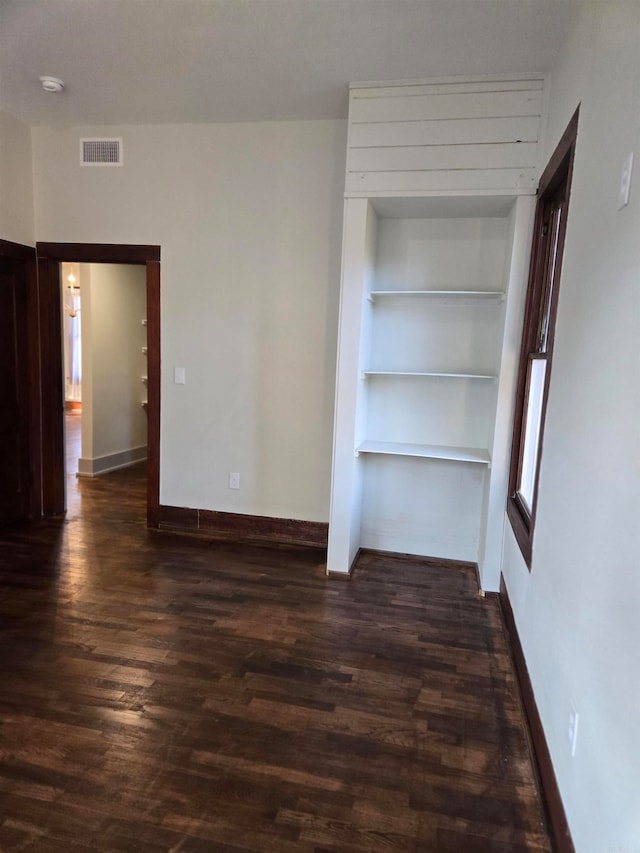 unfurnished room with built in features and dark wood-type flooring