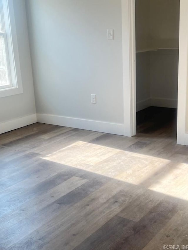 unfurnished bedroom with a closet, a spacious closet, and wood-type flooring