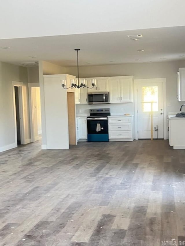 kitchen featuring stainless steel appliances, a notable chandelier, pendant lighting, white cabinetry, and light hardwood / wood-style floors