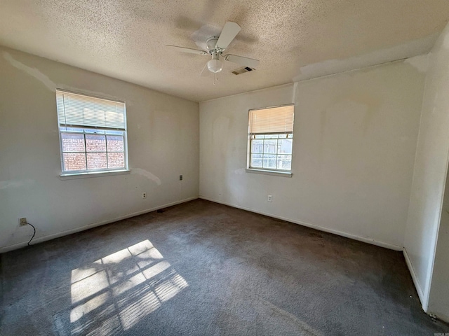 unfurnished room featuring dark colored carpet, a textured ceiling, a healthy amount of sunlight, and ceiling fan