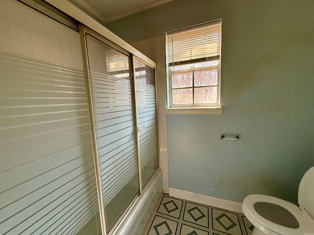 bathroom with toilet, ornamental molding, and shower / bath combination with glass door