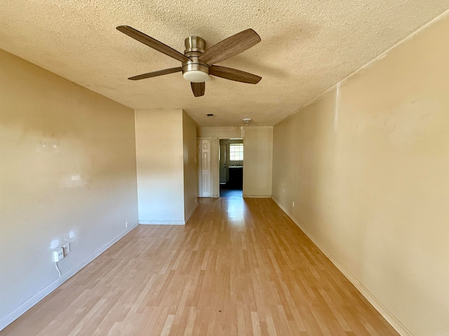 spare room featuring a textured ceiling, light wood-type flooring, and ceiling fan