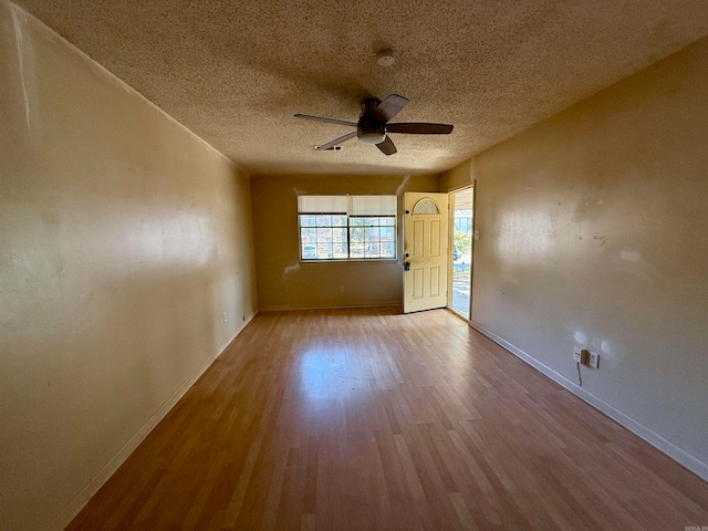 unfurnished room featuring a textured ceiling, light wood-type flooring, and ceiling fan