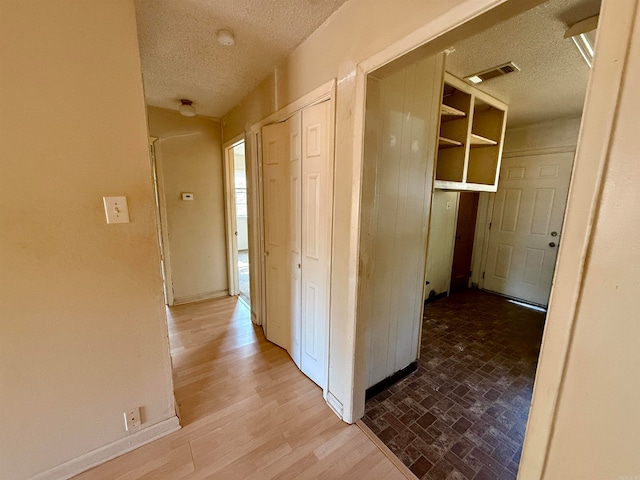 corridor featuring a textured ceiling and light wood-type flooring