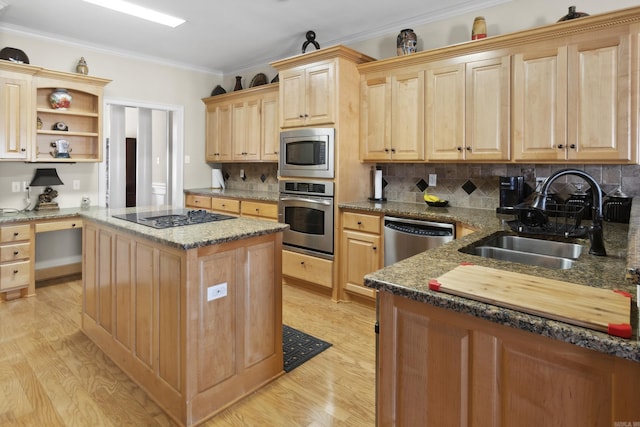 kitchen with stainless steel appliances, a sink, light brown cabinetry, a center island, and light wood-style floors