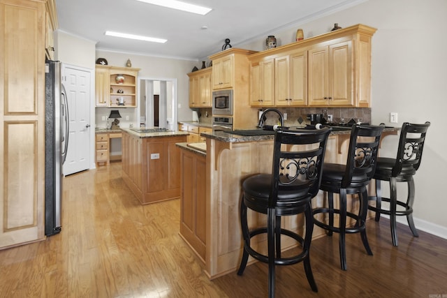 kitchen with a peninsula, open shelves, light brown cabinetry, appliances with stainless steel finishes, and light wood-style floors