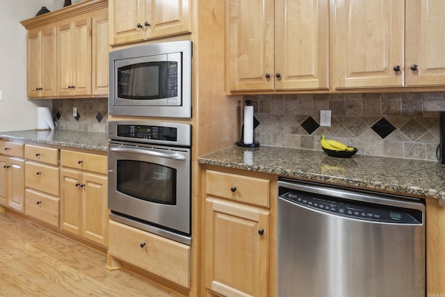 kitchen with stainless steel appliances, light brown cabinets, and tasteful backsplash