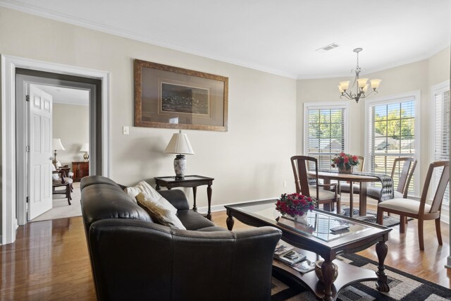 living area featuring a chandelier, dark wood-type flooring, ornamental molding, and baseboards