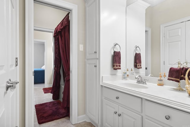 bathroom featuring tile patterned flooring, vanity, connected bathroom, and baseboards