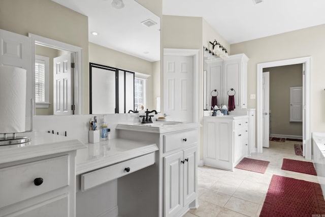 full bathroom with two vanities, a tub, and tile patterned floors