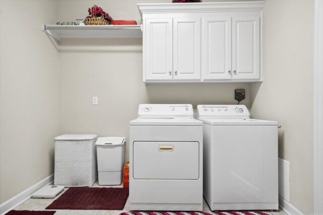 laundry area featuring independent washer and dryer, cabinet space, and baseboards