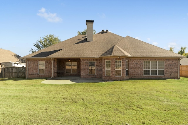 rear view of property with a chimney, a patio, brick siding, and roof with shingles