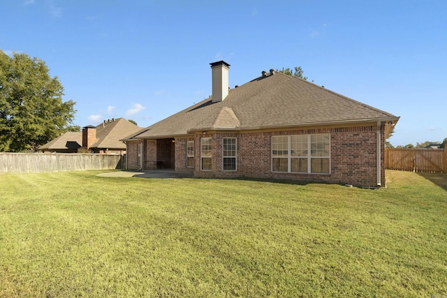 back of house featuring a chimney, a patio area, a shingled roof, and brick siding