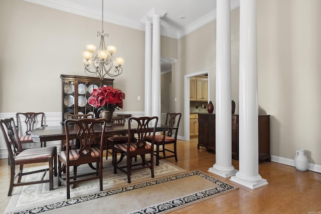dining space with decorative columns, ornamental molding, wood finished floors, a chandelier, and baseboards