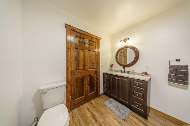 bathroom featuring toilet, vanity, wood-type flooring, and vaulted ceiling