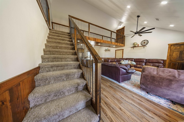 stairs featuring hardwood / wood-style floors, high vaulted ceiling, and ceiling fan