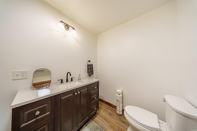 bathroom featuring toilet, vanity, wood-type flooring, and vaulted ceiling