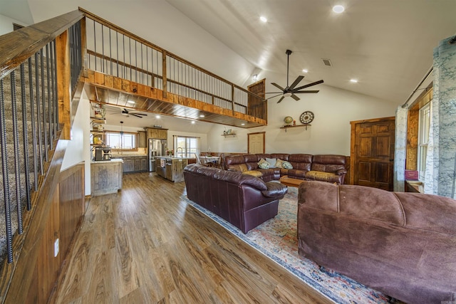 living room with wood-type flooring, high vaulted ceiling, and ceiling fan