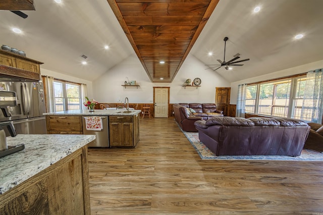 kitchen with appliances with stainless steel finishes, light stone countertops, high vaulted ceiling, light hardwood / wood-style flooring, and sink