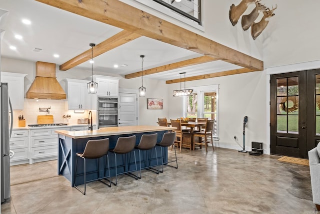 kitchen featuring white cabinetry, stainless steel appliances, a kitchen island with sink, and a healthy amount of sunlight