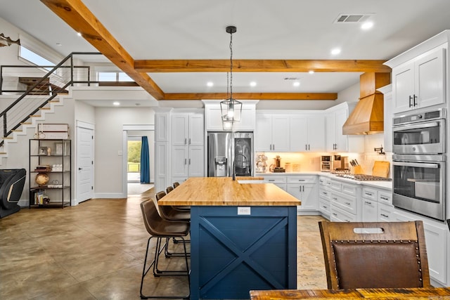 kitchen with appliances with stainless steel finishes, white cabinets, and a kitchen island with sink