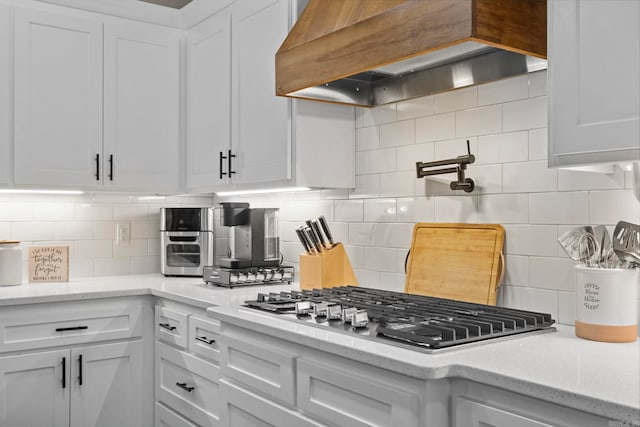 kitchen with white cabinetry, backsplash, and premium range hood