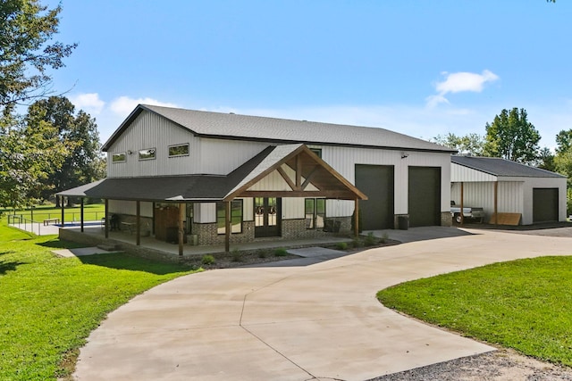 rear view of house featuring covered porch, a lawn, and a garage