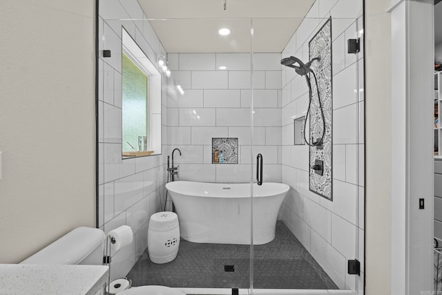 full bathroom with tile walls, separate shower and tub, vanity, and toilet