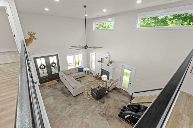 living room featuring french doors, ceiling fan, a healthy amount of sunlight, and light hardwood / wood-style flooring