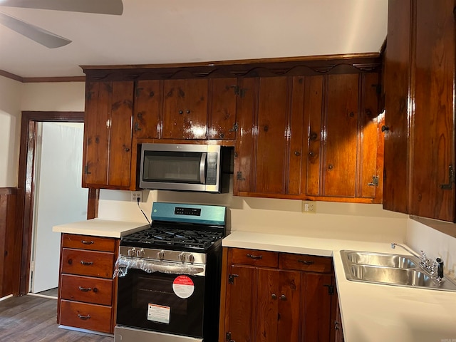 kitchen with appliances with stainless steel finishes, sink, ceiling fan, dark wood-type flooring, and ornamental molding