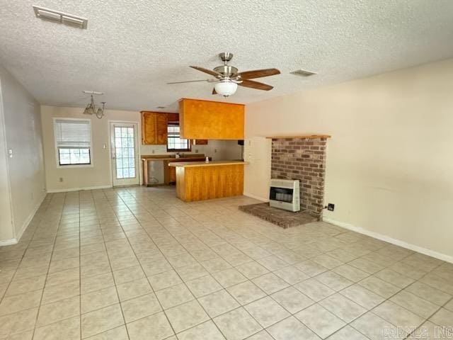 unfurnished living room featuring a fireplace, a textured ceiling, ceiling fan with notable chandelier, and light tile patterned floors