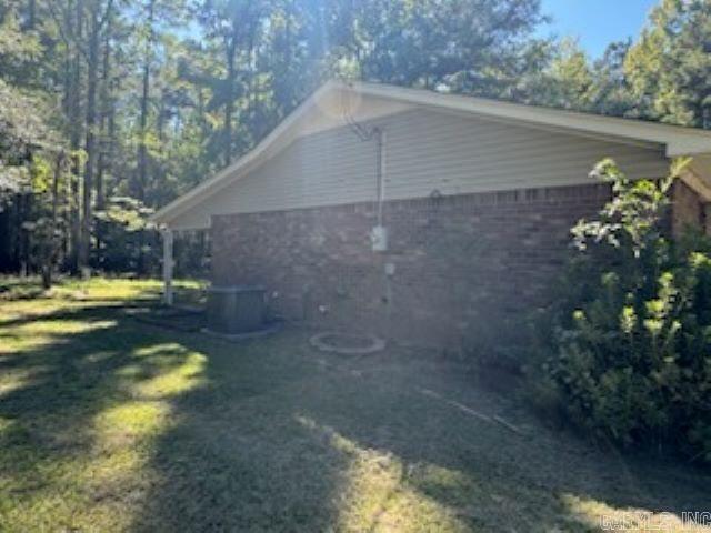 view of property exterior with central AC and a lawn