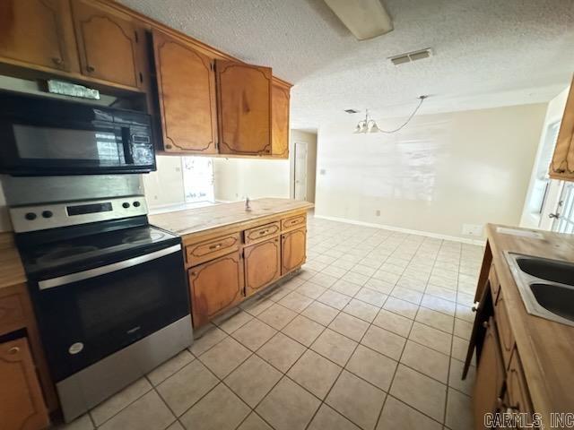 kitchen featuring sink, light tile patterned flooring, a textured ceiling, and electric range