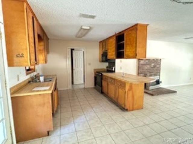 kitchen featuring black range with electric cooktop, a textured ceiling, a breakfast bar area, and light tile patterned floors