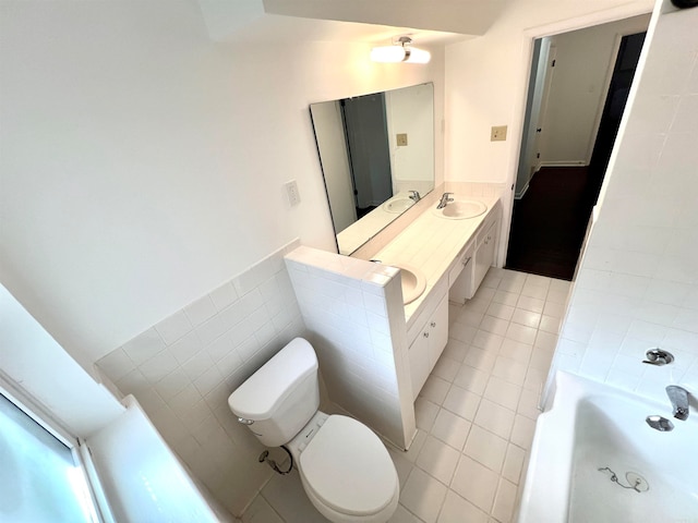 bathroom with tile walls, toilet, vanity, a tub to relax in, and tile patterned floors