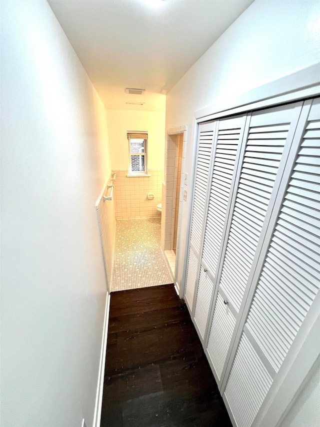 hall with tile walls and dark hardwood / wood-style floors